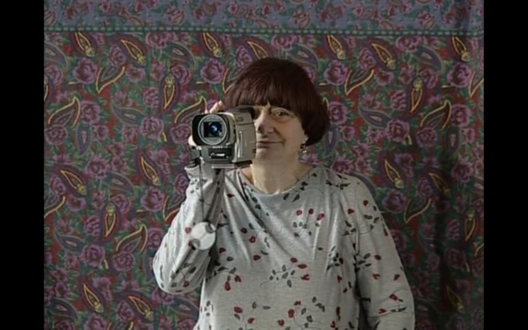 The movie director poses for a self-portrait. She is holding her digital camera in her right hand and looking through the viewfinder